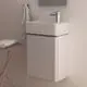 Ideal Standard Armatur in Chrom, montiert an einem weißen Wandbecken mit schmalem Unterbau, daneben ein Handtuch und ein kleiner Tisch mit einem Handtuch.
